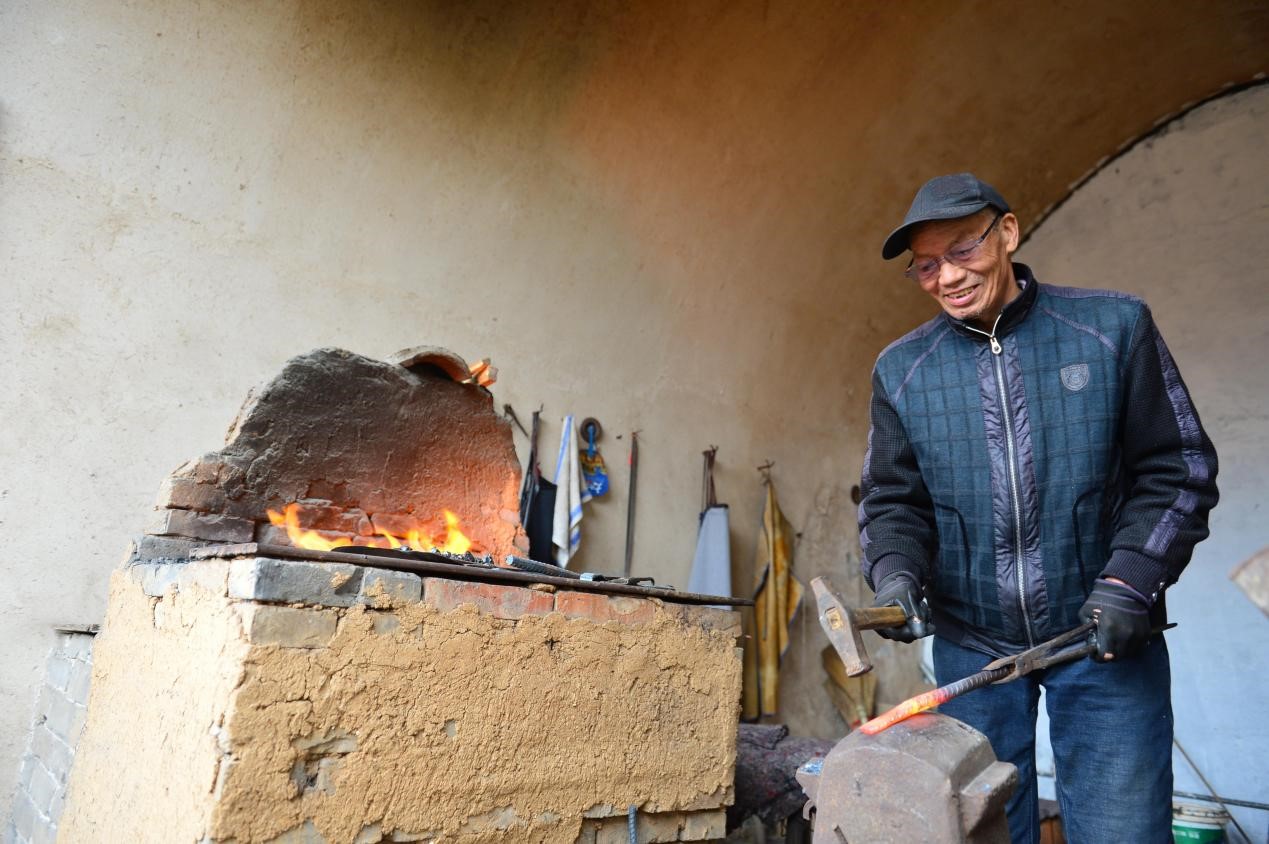 晋城市泽州县大阳古镇,当地自古冶铁业发达,村民向游客展示传统冶铁技术。陈斌摄